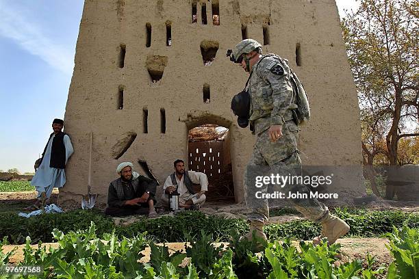 Army Chaplain Carl Subler passes opium poppy farmers while on a military operation on March 14, 2010 at Howz-e-Madad in Kandahar province,...