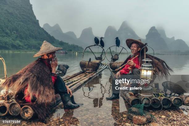 zwei chinesische fischer eine pause auf bambus-floß - pfeife natur stock-fotos und bilder