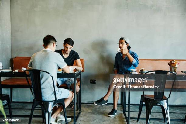 Three friends sharing pastries and coffee at table in bakery