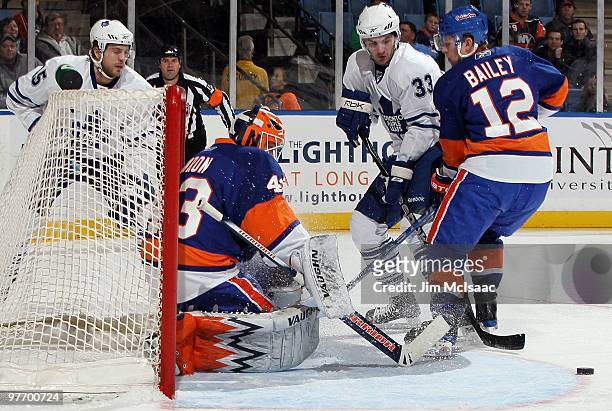 Martin Biron and Josh Bailey of the New York Islanders defend their net against Luca Caputi of the Toronto Maple Leafs on March 14, 2010 at Nassau...