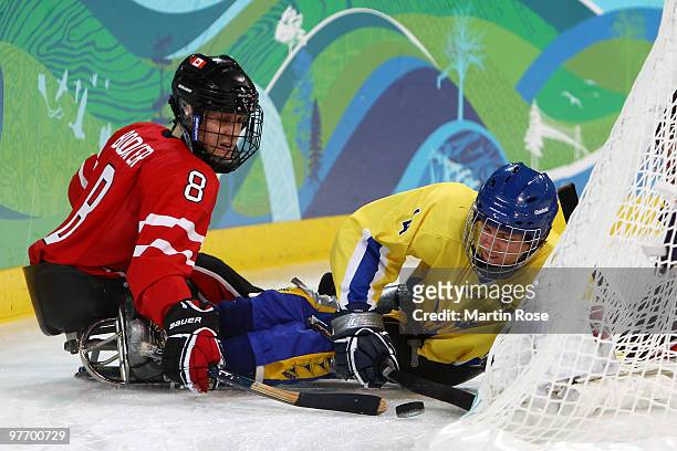 Jeremy Booker of Canada and Aron Anderson of Sweden battle for the puck during the second period of the Ice Sledge Hockey Preliminary Round Group B...