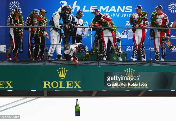 The Toyota Gazoo Racing TS050 Hybrid team driver Fernando Alonso drops a bottle of champagne to team mates as he and co drivers Kazuki Nakajima and...