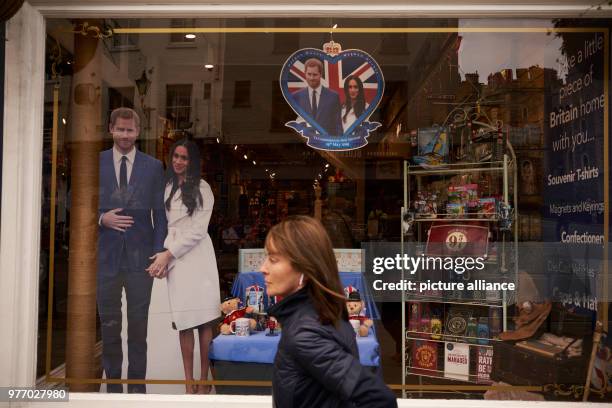 April 2018, Britain, Windsor: A woman walking past a shop of souvenir articles showing prince harry and Meghan Markle. Prince Harry and the American...