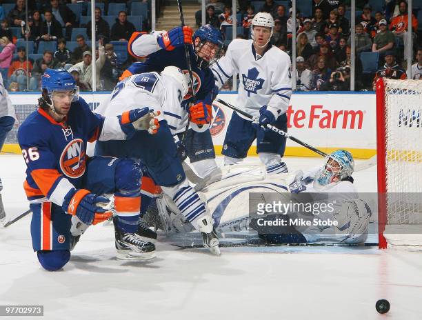 Tim Jackman and Matt Moulson of the New York Islanders keep their eye on the puck as goaltender Jean-Sebastien Giguere of the Toronto Maple Leafs...