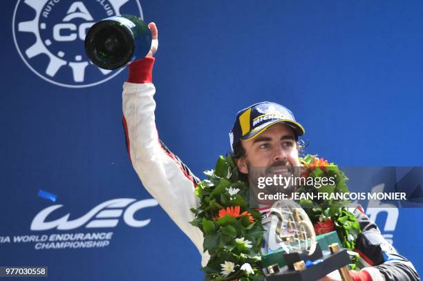 Spain's driver Fernando Alonso celebrates on the podium with his trophy after winning the 86th Le Mans 24-hours endurance race, at the Circuit de la...