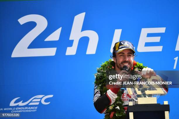 Spain's driver Fernando Alonso celebrates on the podium with his trophy after winning the 86th Le Mans 24-hours endurance race, at the Circuit de la...