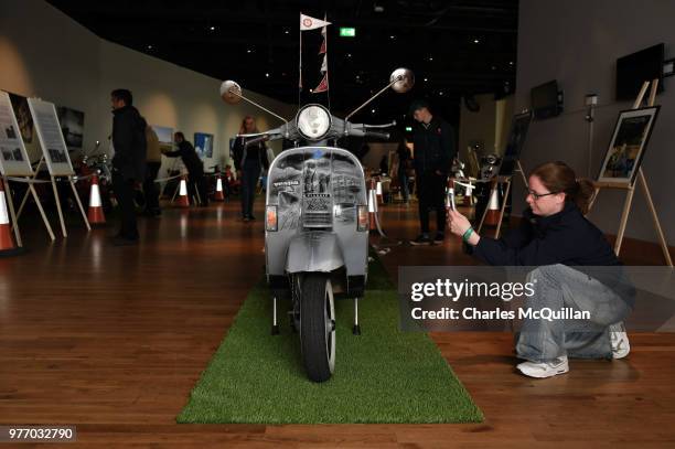 Woman takes a photograph of the 'Titanic' Vespa on display in Titanic Belfast as the 2018 Vespa International World Days event takes place at the...