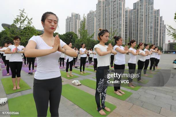 About a hundred people gather to do yoga at Zhuge Liang Square in the morning on June 17, 2018 in Xiangyang, Hubei Province of China. Yoga...