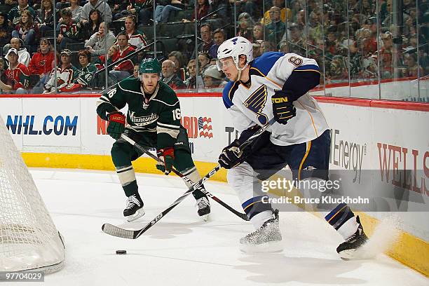 Erik Johnson of the St. Louis Blues handles the puck with Andrew Ebbett of the Minnesota Wild defending during the game at the Xcel Energy Center on...