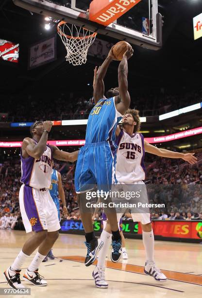 Emeka Okafor of the New Orleans Hornets puts up a shot over Amar'e Stoudemire and Robin Lopez of the Phoenix Suns during the NBA game at US Airways...