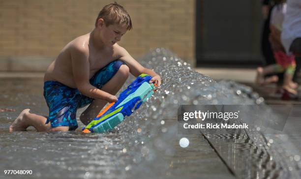 Young boy takes a minutes to refill his water gun. Kids enjoy the large splash pad in front of Mississauga City Hall to beat the heat of the day....