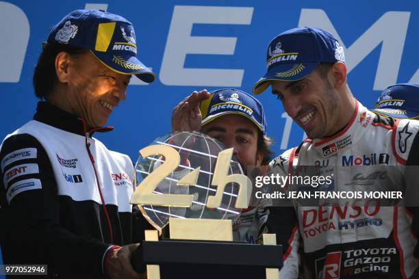 Spain's driver Fernando Alonso , Swiss driver Sebastien Buemi and Toyota's head of motorsport, Shigeki Tomoyama celebrate with the trophy on the...