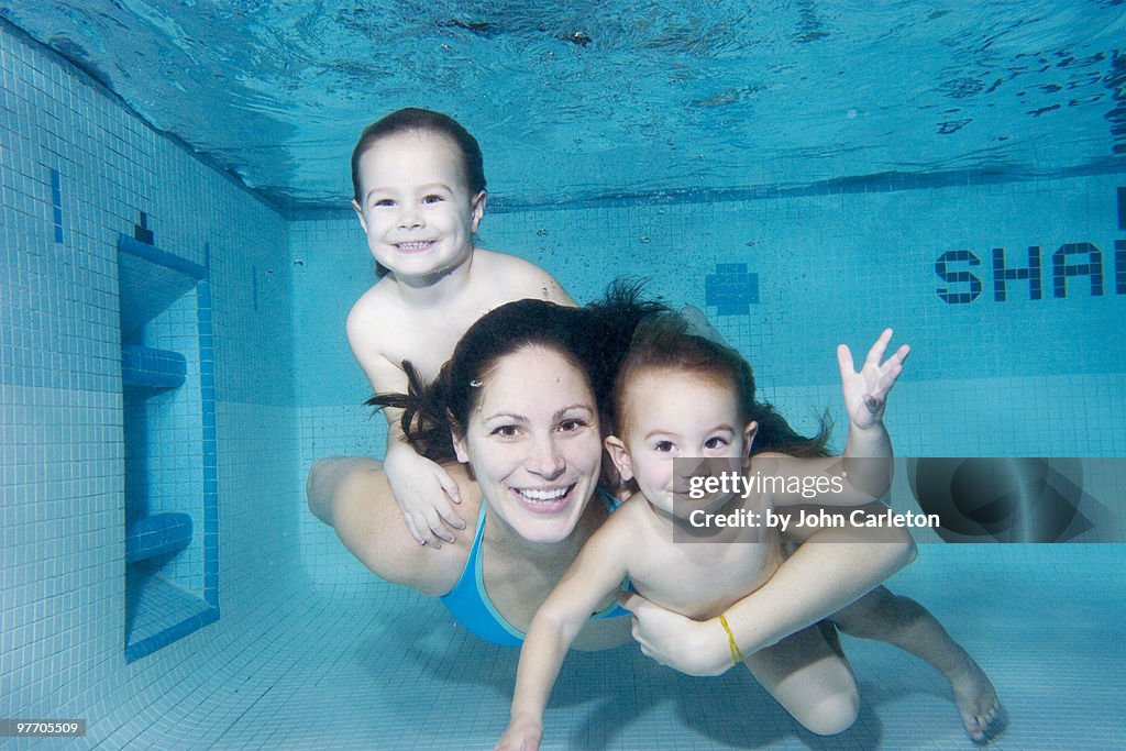 Mom and two kids swimming underwater