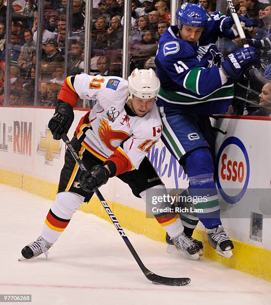 Andrew Alberts of the Vancouver Canucks crashes into the end boards after getting hit by Niklas Hagman of the Calgary Flames during the third period...