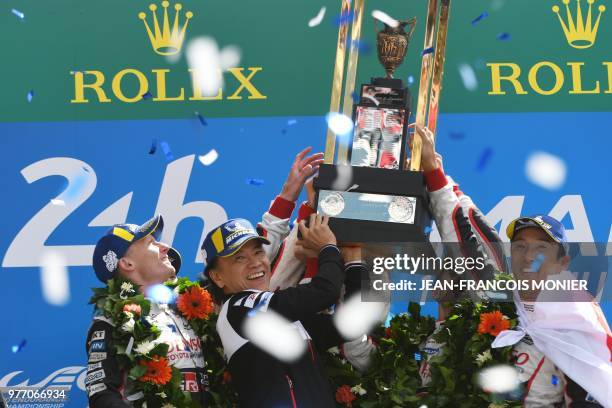 Toyota's head of motorsport, Shigeki Tomoyama and Japanese driver Kazuki Nakajima celebrate with their trophy on the podium after winning the 86th...