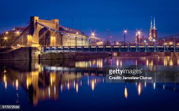 illuminated bridge reflecting in river at night, wroclaw, lower silesia, poland - wroclaw photos et images de collection