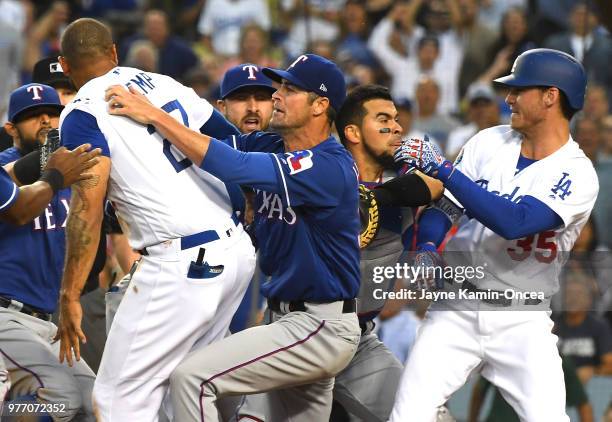 Cole Hamels of the Texas Rangers along with Cody Bellinger of the Los Angeles Dodgers try to hold back Matt Kemp of the Los Angeles Dodgers as...