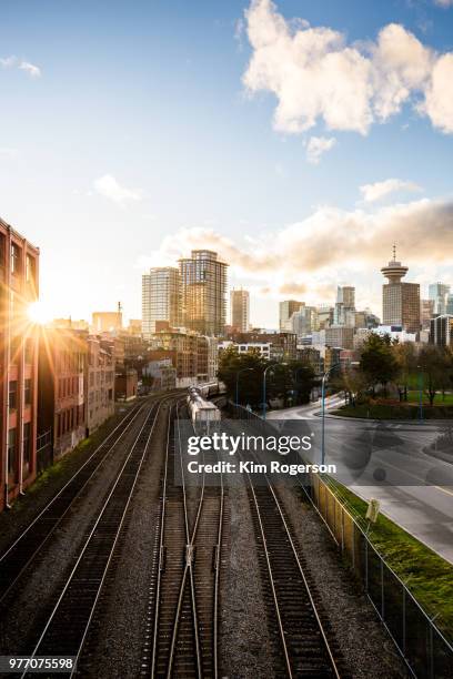 railroad tracks with sunburst await the transport trains into vancouver - downtown vancouver stock pictures, royalty-free photos & images