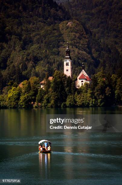 tranquil scene with people in boat on lake bled and church in background, bled, slovenia - lago di bled foto e immagini stock