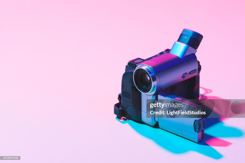 Close up view of digital video camera on pink background