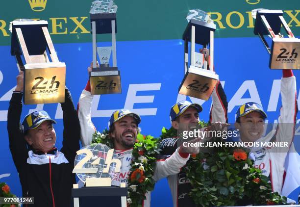 Toyota's head of motorsport, Shigeki Tomoyama, Spain's driver Fernando Alonso, Switzerland's Sebastien Buemi and Japan's Kazuki Nakajima celebrate...