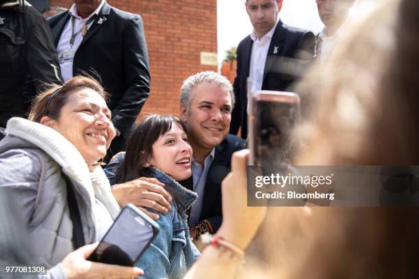 Ivan Duque, presidential candidate for the Democratic Center Party, center, takes photographs with voters outside of a polling center during the...