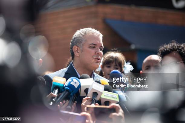 Ivan Duque, presidential candidate for the Democratic Center Party, center, speaks to members of the media outside of a polling center after casting...