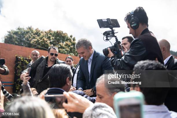 Ivan Duque, presidential candidate for the Democratic Center Party, center, greets voters outside of a polling center during the second round of...