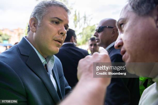 Ivan Duque, presidential candidate for the Democratic Center Party, listens as a voter speaks outside of a polling station during the second round of...