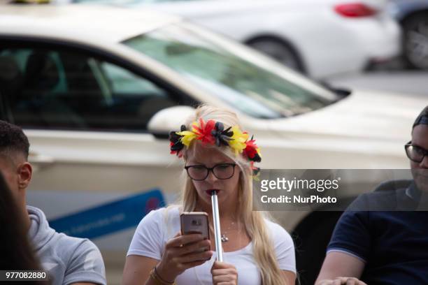 Woman with a flower chain with the German colors on the head watches on her phone. Some impressions of the fans watching the Germany vs Mexico match...