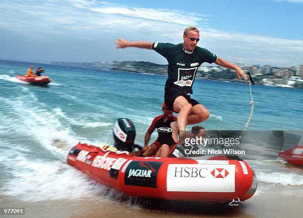 Eddie Irvine of Northern Ireland jumps from a IRB rescue boat onto Bondi Beach, Sydney during some races with JaguarF1 teammate Luciano Burti of...