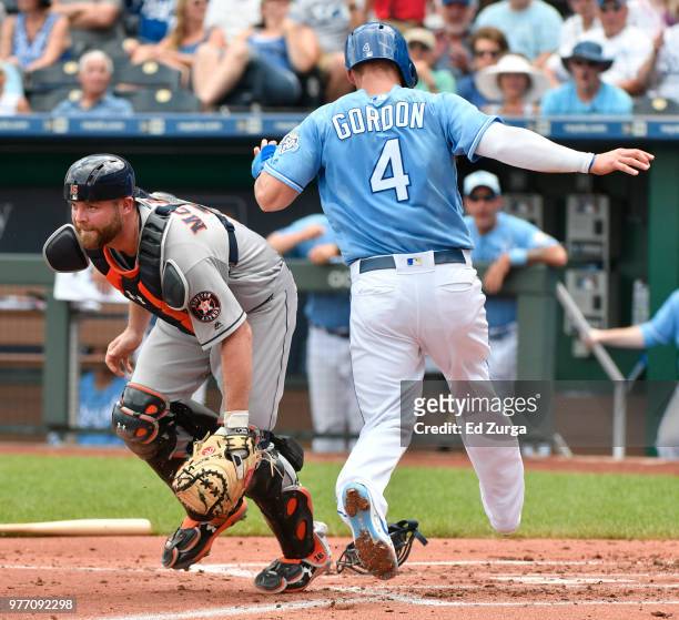 Alex Gordon of the Kansas City Royals scores past Brian McCann of the Houston Astros in the first inning at Kauffman Stadium on June 17, 2018 in...