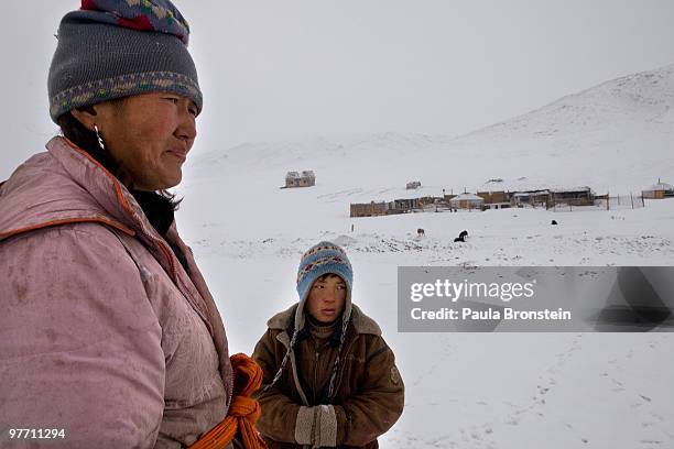 Dealing with another snowstorm, Battsetseg and her son Munkhbayar stand outside their home on March 15, 2010 in Zuunmod in Tuv province, Mongolia....