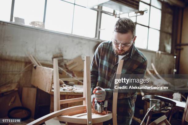 young carpenter sawing and repairing broken chair - broken chair stock pictures, royalty-free photos & images