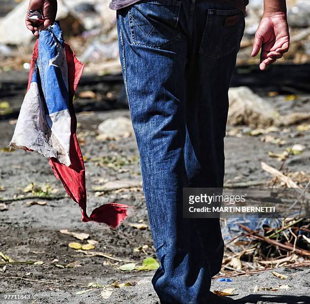 Local resident holds a frayed Chilean flag in Constitucion, some 300 km south of Santiago, March 4, 2010. The official death toll from Saturday's...