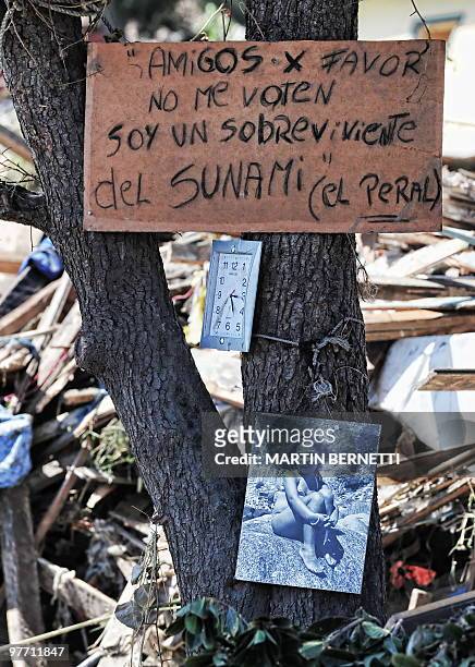 Clock stopped at the time of the earthquake and a photograph of a survivor hang from a tree in Constitucion, some 300 km south of Santiago, March 4,...