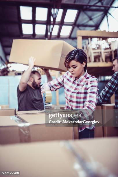 team av lagerarbetare tejpning lådor och förbereda för frakt - garment factory bildbanksfoton och bilder