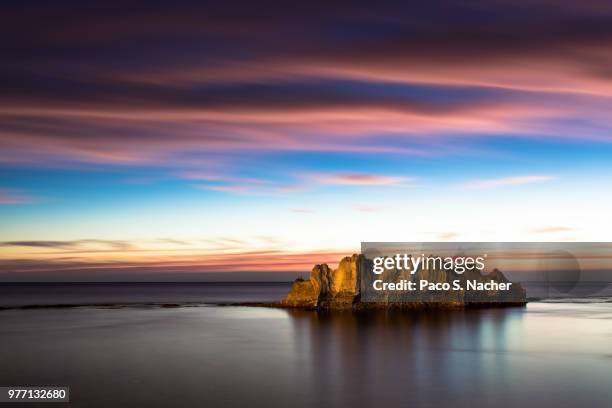 a rock island in the sea at sunset. - denia 個照片及圖片檔