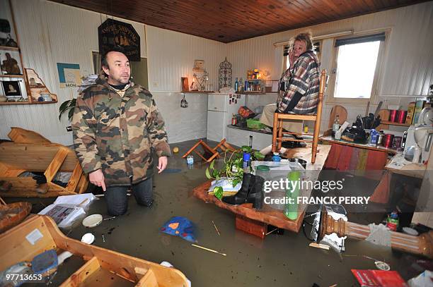 Two persons wait for rescuers in their kitchen on February 28 as a result of heavy floods, in La Faute-sur-Mer western France. Dubbed "Xynthia", the...