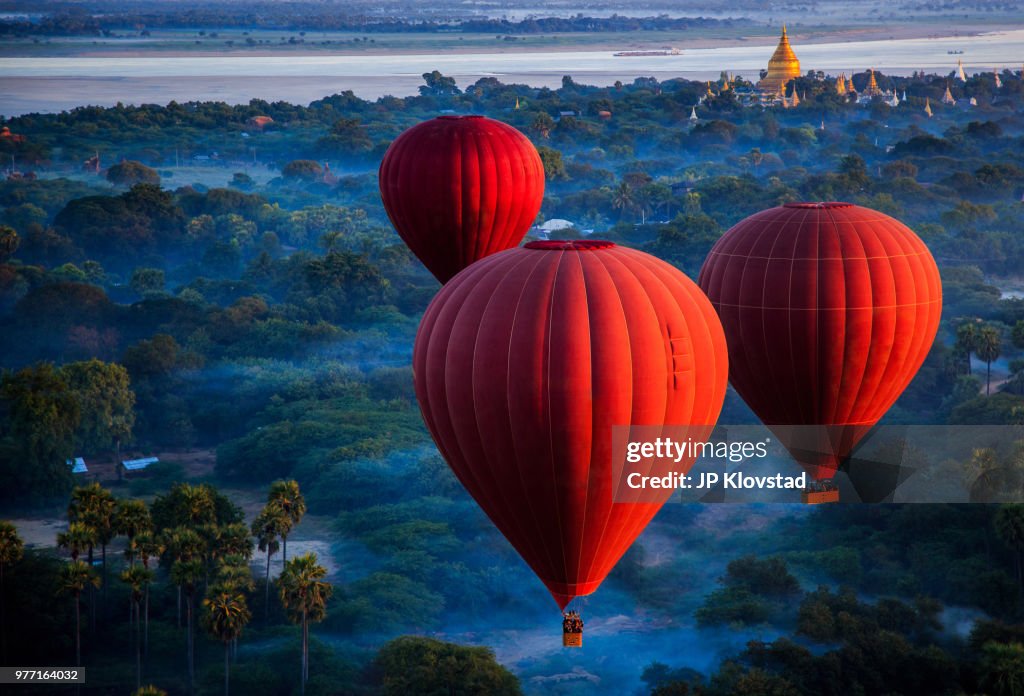 Red hot air balloons over jungle, Nyaung-U, Mandalay Region, Myanmar