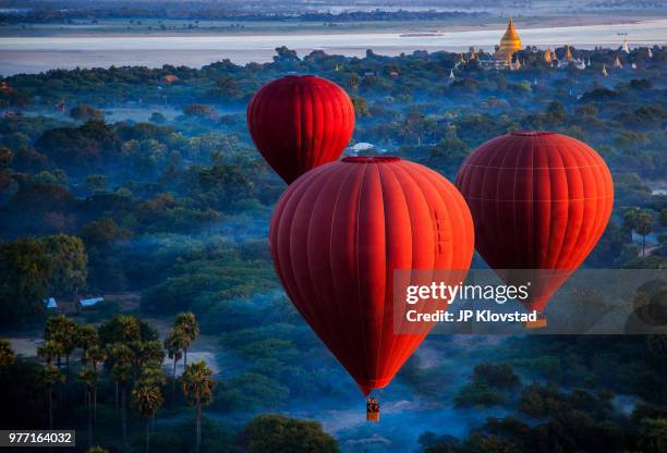 red hot air balloons over jungle, nyaung-u, mandalay region, myanmar - air balloon imagens e fotografias de stock