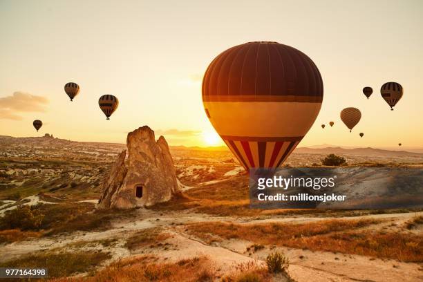 heißluft ballons fliegen bei sonnenuntergang, kappadokien, türkei - cappadocia hot air balloon stock-fotos und bilder
