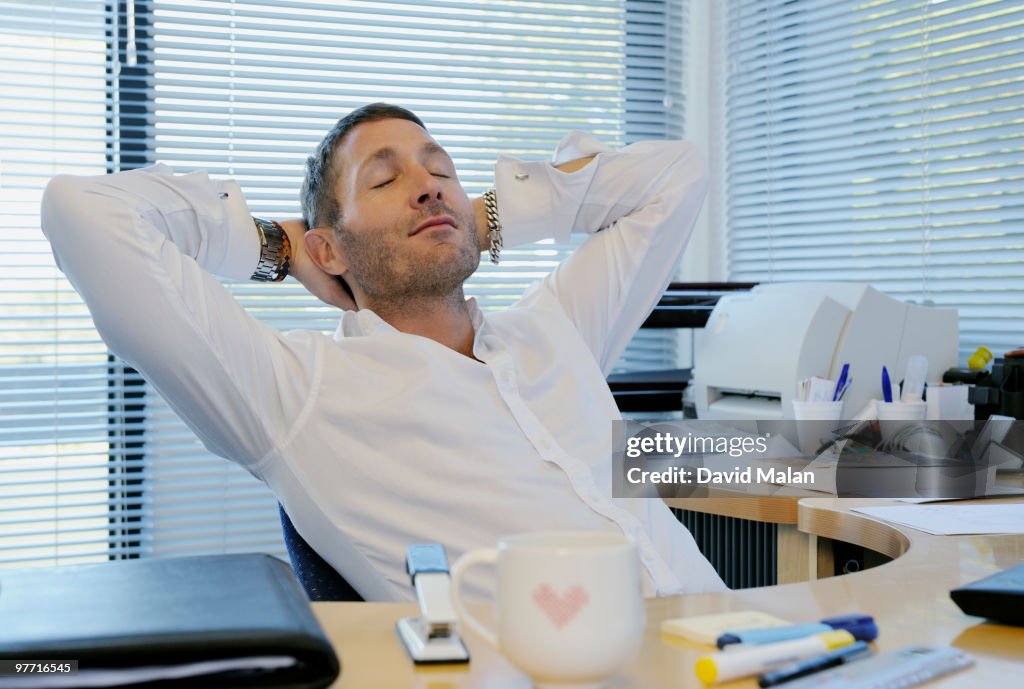 Man relaxing at his desk in office environment