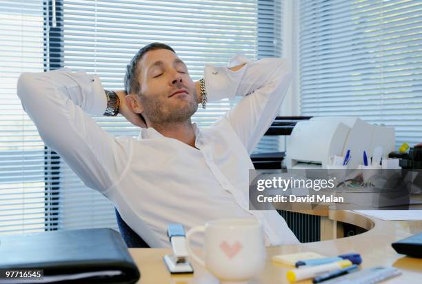 man relaxing at his desk in office environment - hands behind back stock pictures, royalty-free photos & images