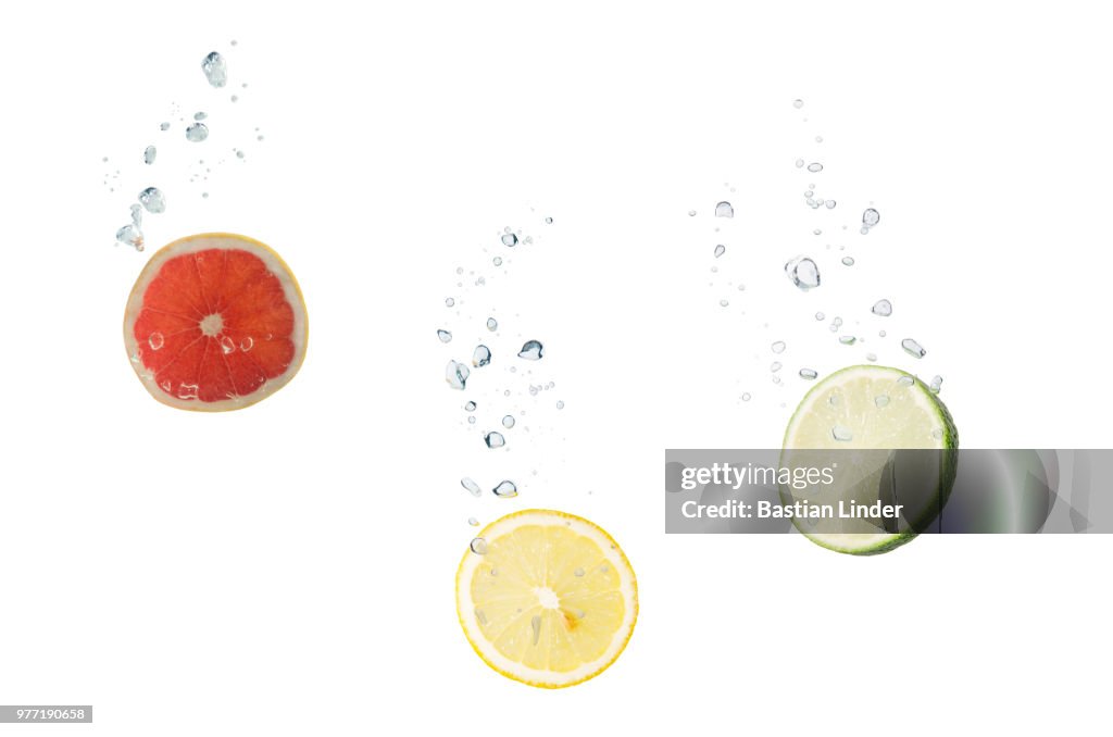 Grapefruit, lemon, lime in water with air bubbles