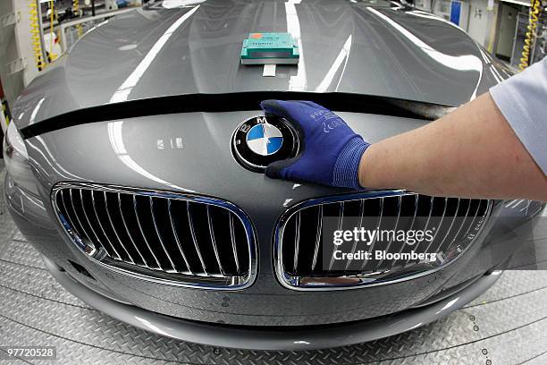 Bayerische Motoren Werke AG employee puts the hood ornament logo on a 5-series automobile at the company's factory in Dingolfing, Germany, on Monday,...