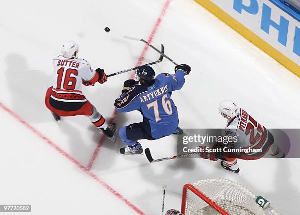 Evgeny Artyukhin of the Atlanta Thrashers battles for the puck against Brandon Sutter of the Carolina Hurricanes at Philips Arena on March 7, 2010 in...