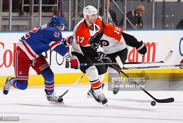 Jeff Carter of the Philadelphia Flyers skates with the puck under pressure in the second period by Artem Anisimov of the New York Rangers on March...