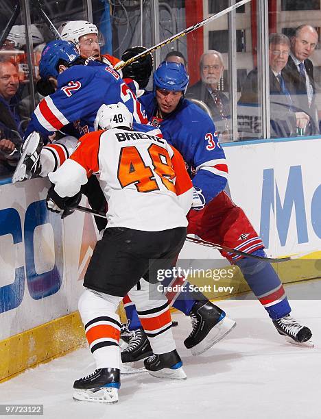 Brian Boyle and Michal Rozsival of the New York Rangers check their opponent of the Philadelphia Flyers into the boards in the second period on March...