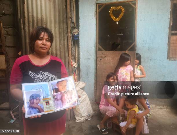 April 2018, Philippines, Manila: The Filipino Emily Soriano showing photos in front of her house in Bagong Silang of her son who was shot. The 15...
